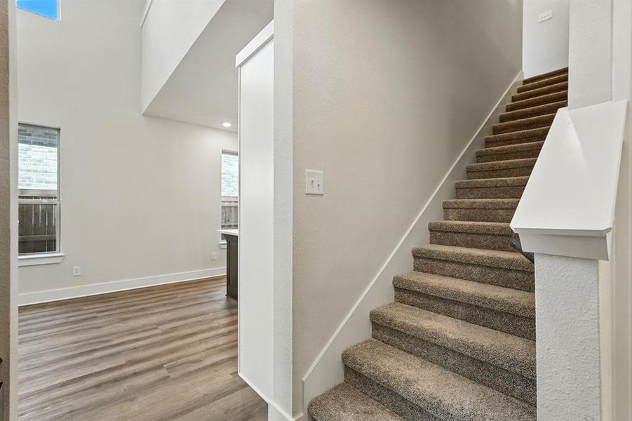 Stairs with wood finished floors, plenty of natural light, recessed lighting, and a high ceiling Stairs with wood finished floors, plenty of natural light, recessed lighting, and a high ceiling