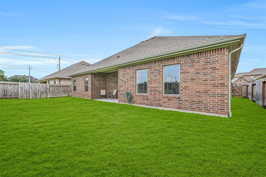 A final view showcases the home's brick rear exterior, covered patio and expansive lawn, with multiple rear-facing windows connecting the light-filled interior living spaces to the backyard. A final view showcases the home's brick rear exterior, covered patio and expansive lawn, with multiple rear-facing windows connecting the light-filled interior living spaces to the backyard.