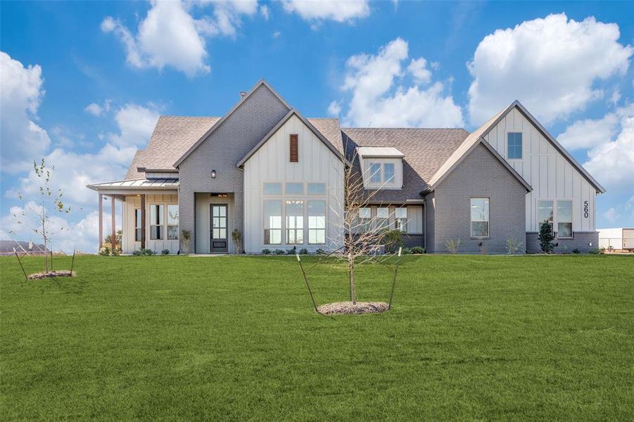 Back of property with board and batten siding, brick siding, a lawn, and a standing seam roof Back of property with board and batten siding, brick siding, a lawn, and a standing seam roof