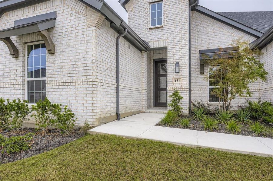 Doorway to property featuring brick siding and a yard Doorway to property featuring brick siding and a yard