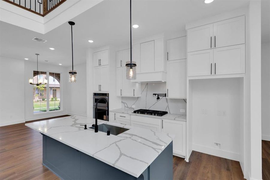 Kitchen featuring dark wood-type flooring, appliances with stainless steel finishes, white cabinetry, pendant lighting, and recessed lighting Kitchen featuring dark wood-type flooring, appliances with stainless steel finishes, white cabinetry, pendant lighting, and recessed lighting