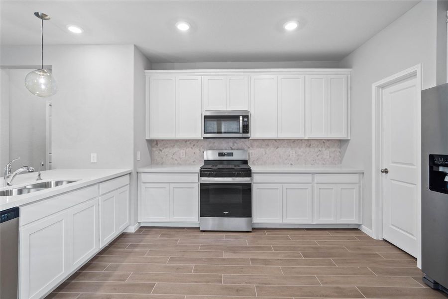 Expansive countertops provide a clean, horizontal sweep that beautifully highlights the intricate patterns of the Mosaix Daphne White Herringbone backsplash.