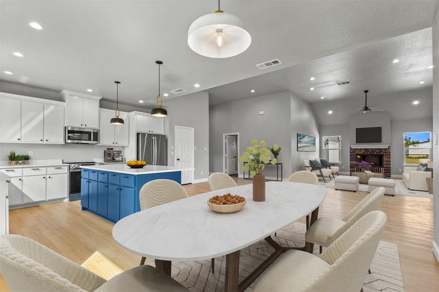 Dining room with recessed lighting, a fireplace, light wood finished floors, ceiling fan, and high vaulted ceiling