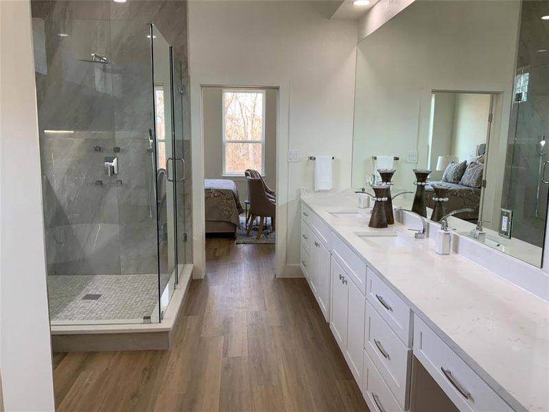 Ensuite bathroom with vanity, a marble finish shower, and dark wood finished floors Ensuite bathroom with vanity, a marble finish shower, and dark wood finished floors