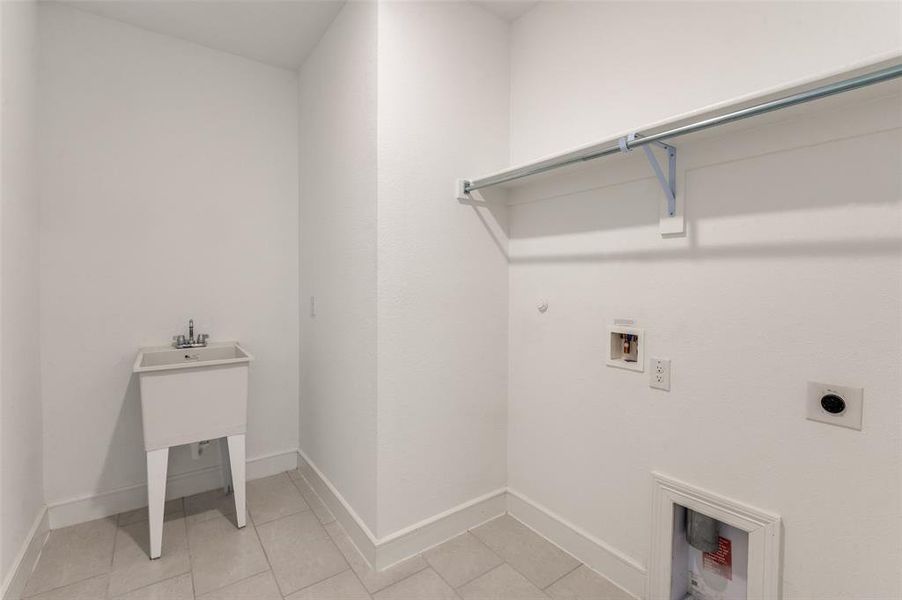 Laundry area featuring gas dryer hookup, washer hookup, light tile patterned floors, and hookup for an electric dryer Laundry area featuring gas dryer hookup, washer hookup, light tile patterned floors, and hookup for an electric dryer