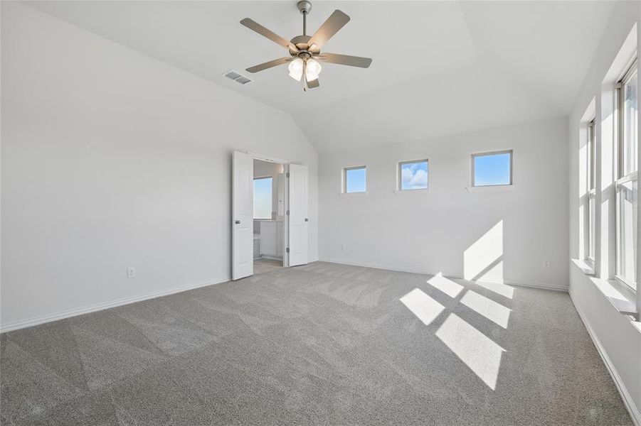 Unfurnished bedroom featuring light carpet, a ceiling fan, and lofted ceiling