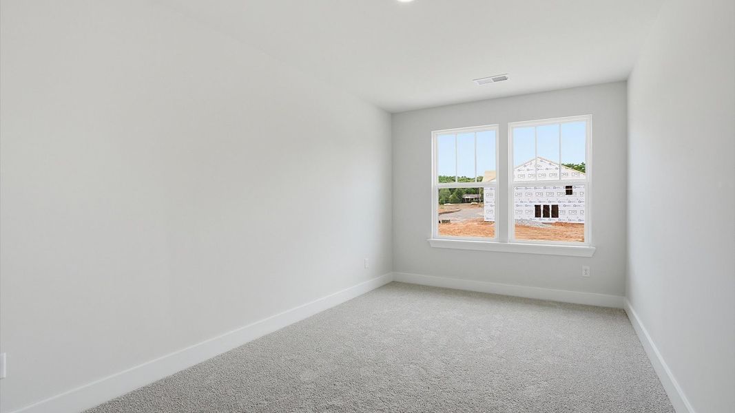 Accomplished bedroom layout with cozy carpet, a spacious walk-in closet, and sun-filled windows in Simpsonville, SC