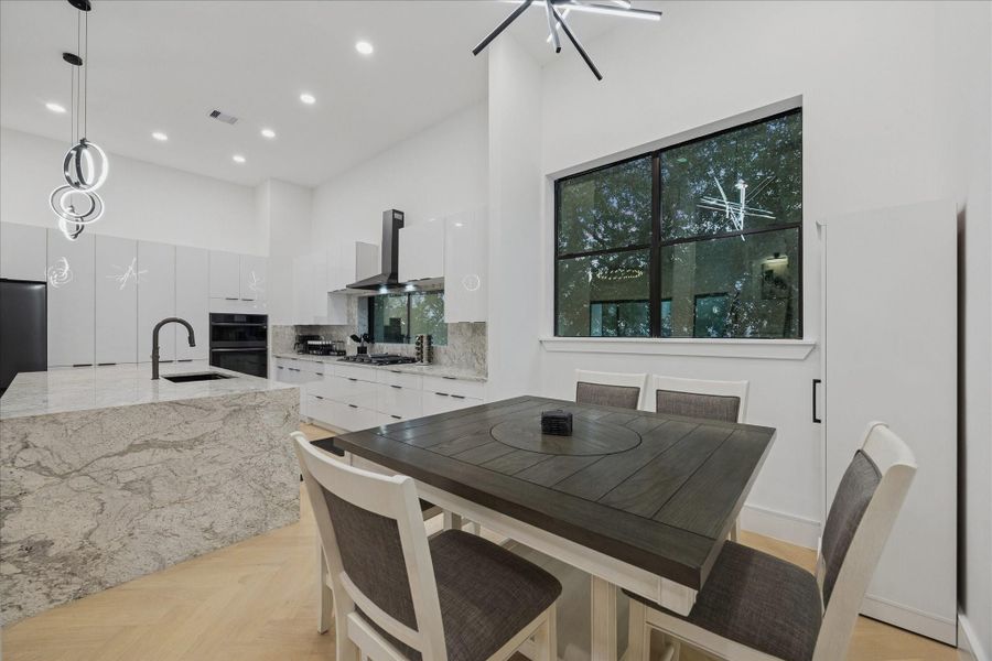 Dining area just off the kitchen featuring soaring ceilings, oversized windows, and designer lighting—an inviting space for everyday meals and effortless entertaining.