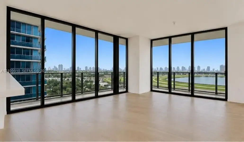 Floor-to-ceiling windows with black frames, wood-finish flooring, and expansive wrap-around balconies