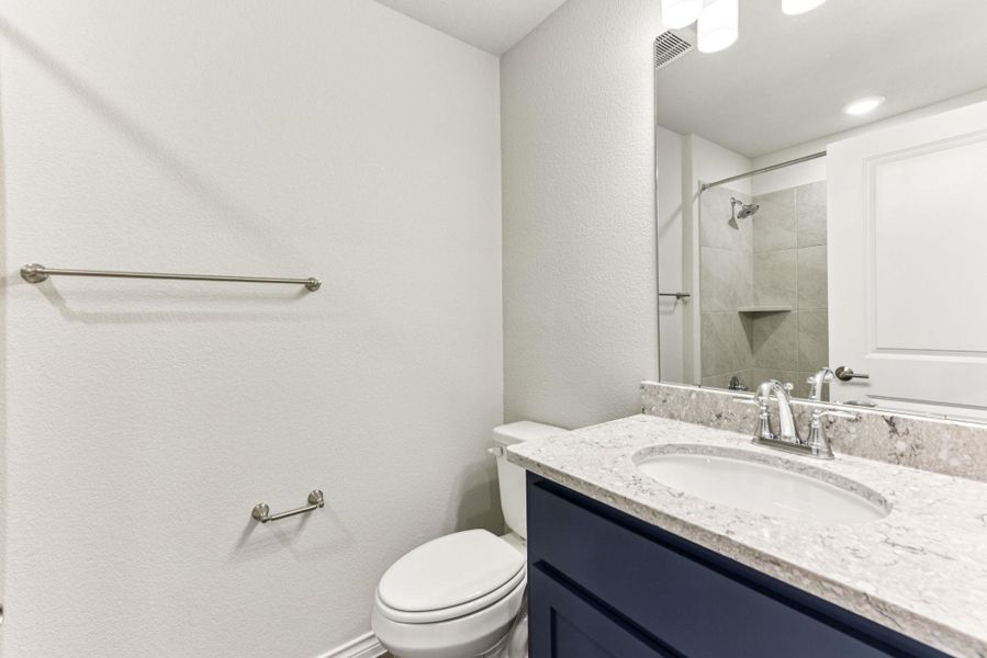 Bathroom with a textured wall, vanity, and tiled shower Bathroom with a textured wall, vanity, and tiled shower