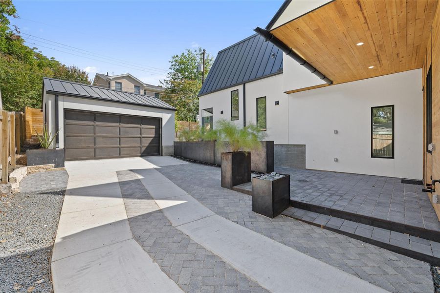 View of side of home with a standing seam roof, an outdoor structure, a patio area, and stucco siding