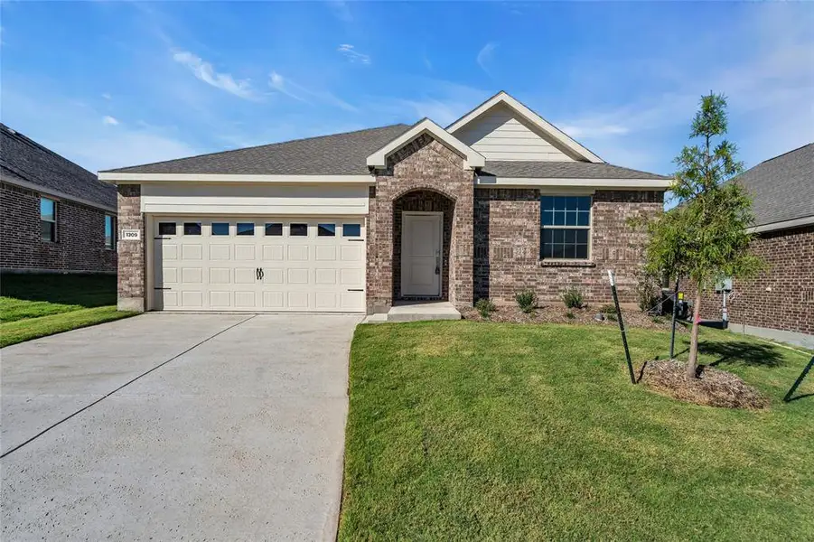 View of front of property featuring a front lawn and a garage