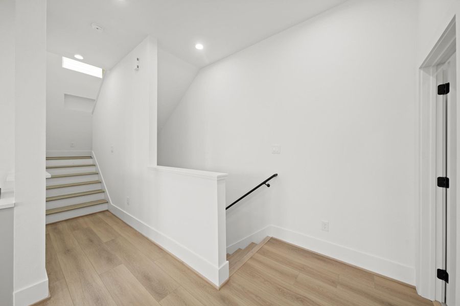 The landing and stairwell with wood treads lead to the third floor which also features white oak luxury vinyl plank flooring throughout. Midway up the stairs is a window allowing natural light to flow into the stairway.