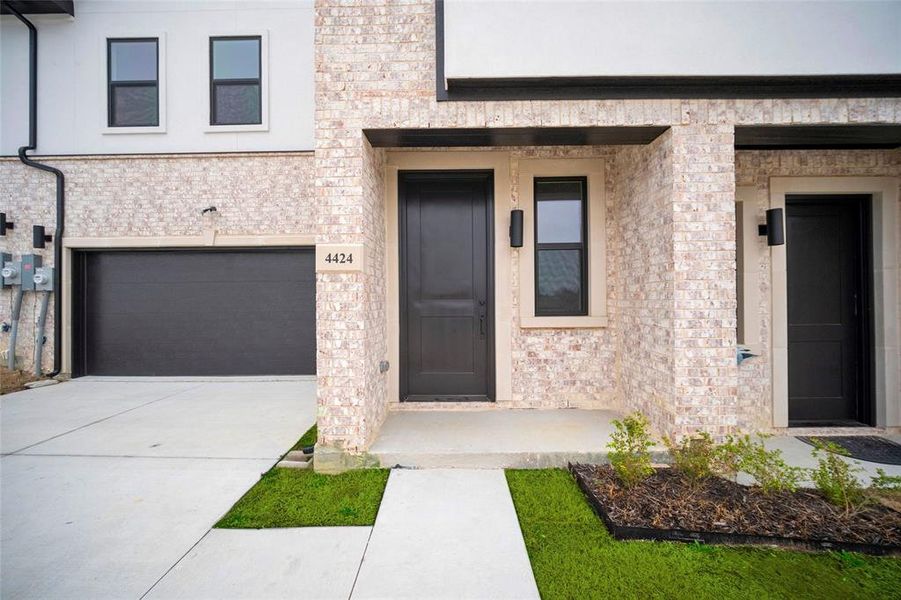 Property entrance with concrete driveway and an attached garage