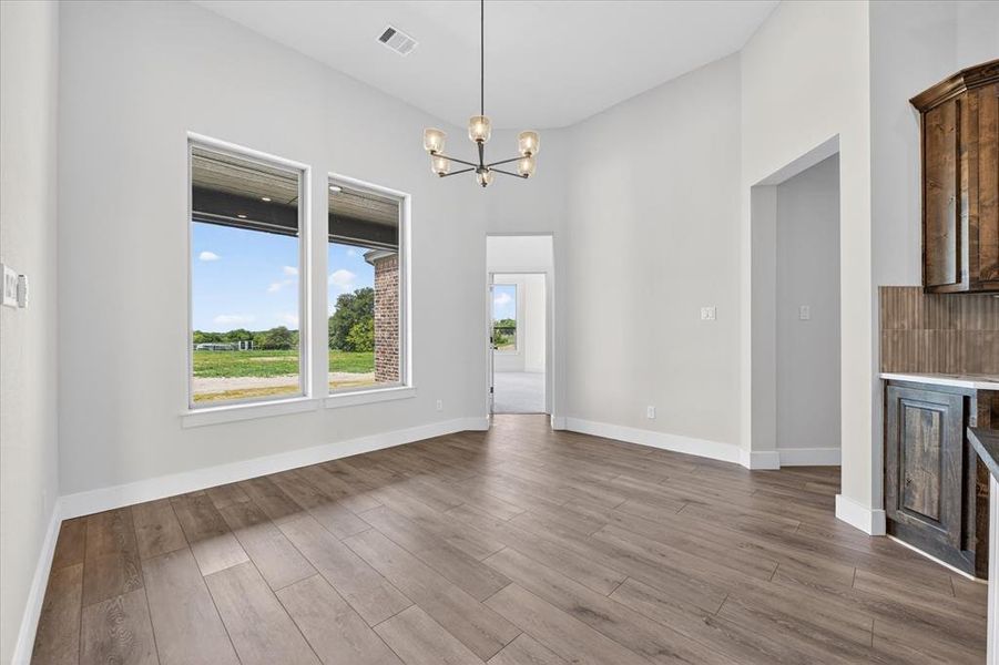 Unfurnished dining area with hanging lights, dark wood finished floors, and a high ceiling