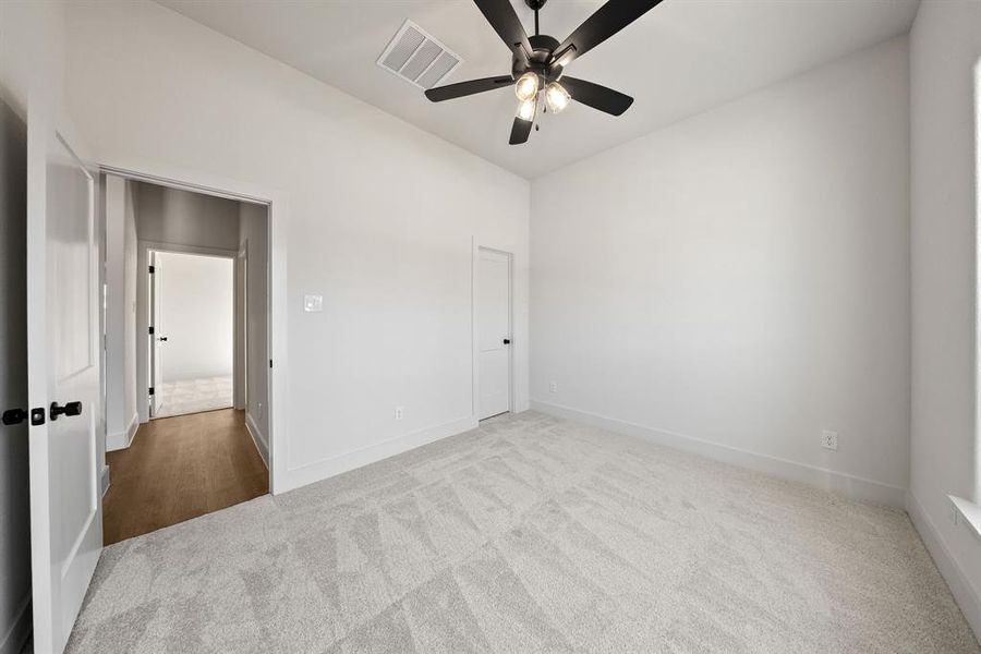 Unfurnished bedroom with light carpet, a ceiling fan, and vaulted ceiling