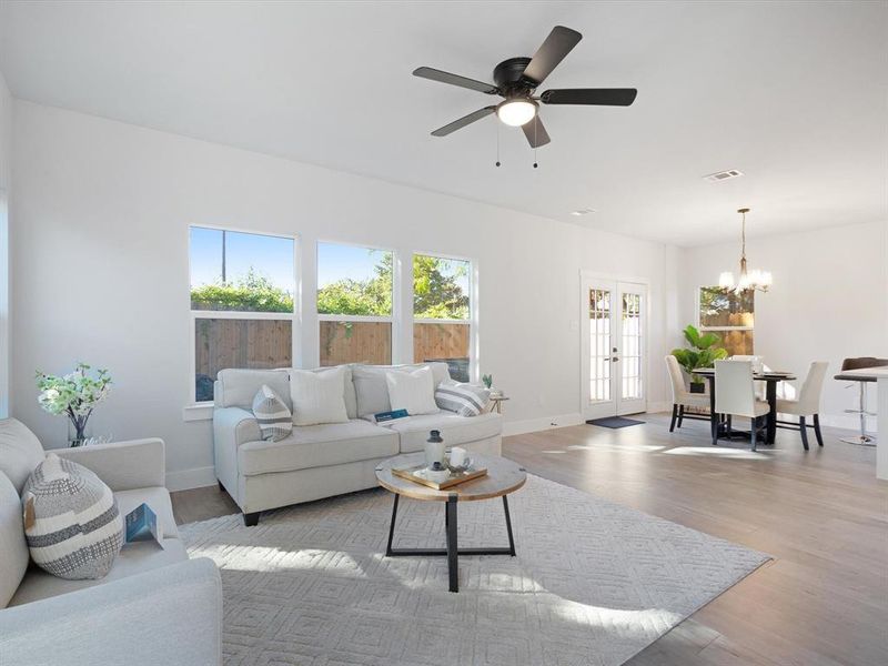 Living room with ceiling fan with notable chandelier, french doors, and light hardwood / wood-style flooring