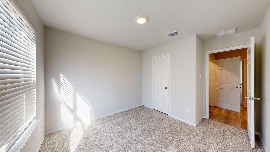 Carpeted room featuring a window with horizontal blinds, an overhead recessed light, and a white paneled door