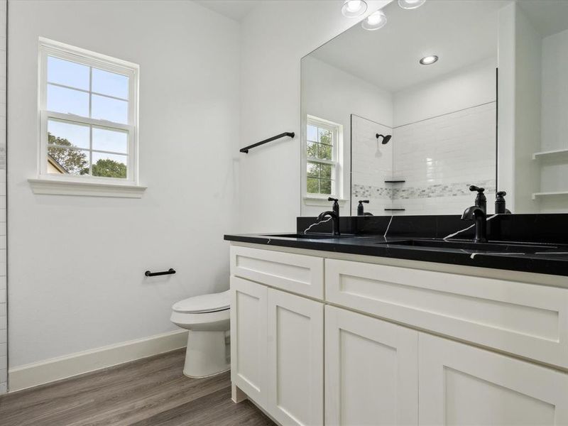 Bathroom with double vanity, toilet, and hardwood / wood-style flooring