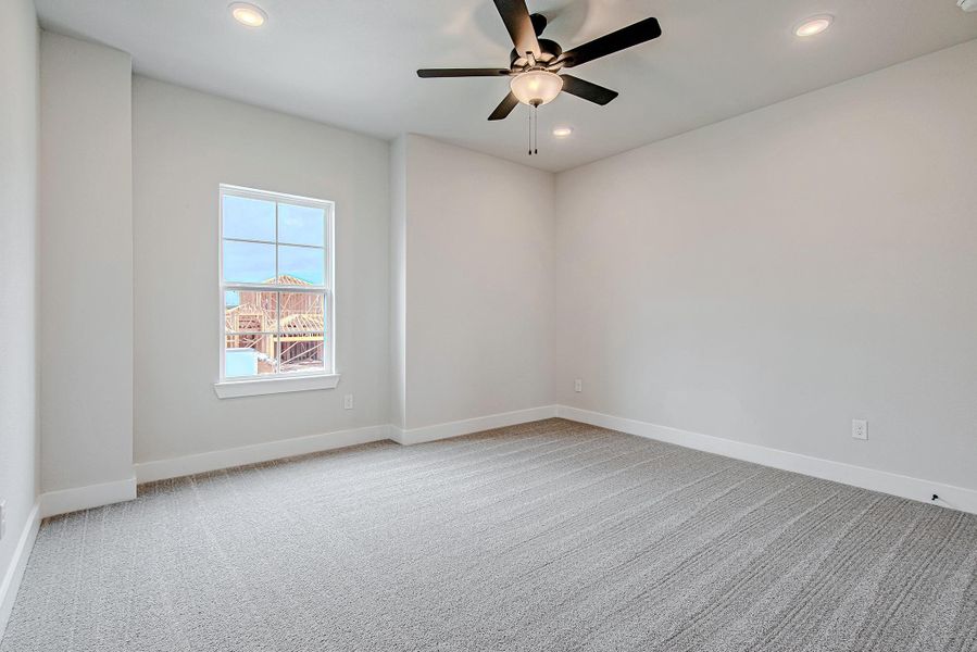 Another angle of the spacious bedroom featuring neutral tones and ceiling fan.