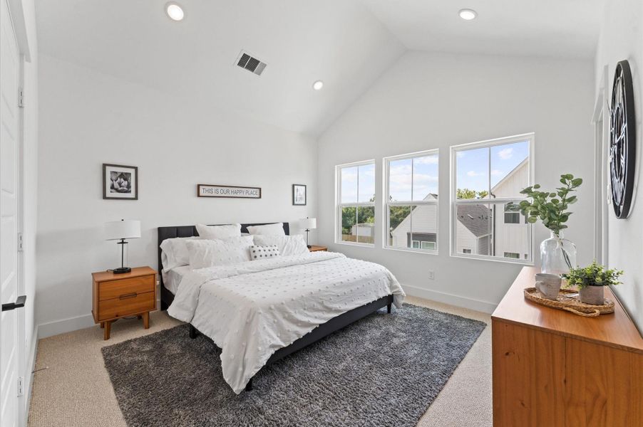 Retreat to the luxurious primary bedroom where soaring ceilings and expansive windows create an airy, light-filled sanctuary.