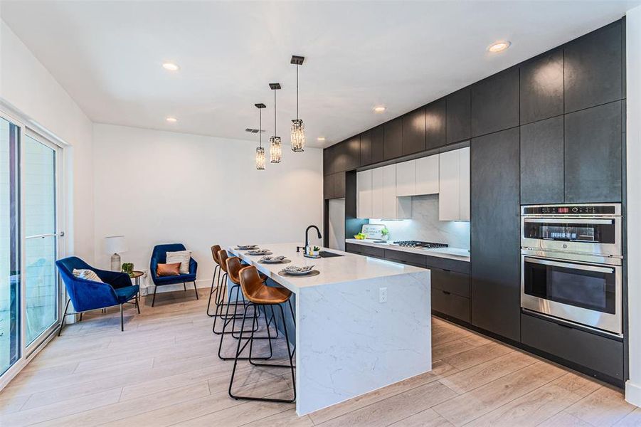 Kitchen with a kitchen breakfast bar, hanging light fixtures, modern cabinets, a center island with sink, and recessed lighting Kitchen with a kitchen breakfast bar, hanging light fixtures, modern cabinets, a center island with sink, and recessed lighting