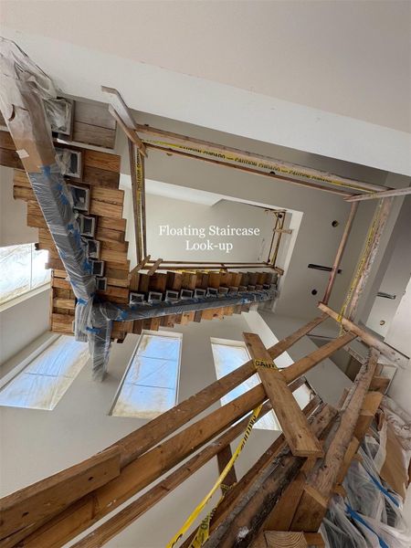 Architectural centerpiece with a dramatic floating staircase, soaring upward through multiple levels, enhanced by abundant natural light.