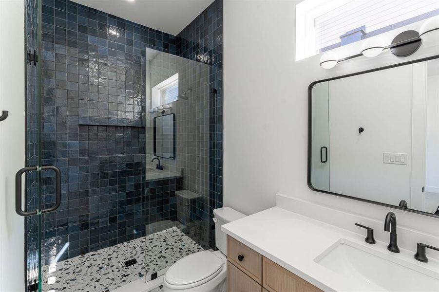 Bathroom featuring walk in shower, vanity, and toilet