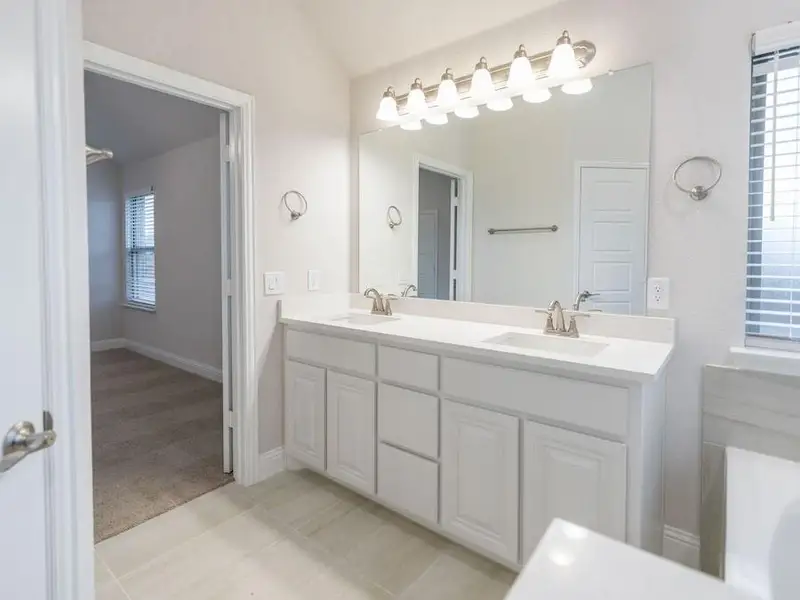 Bathroom featuring tile patterned flooring, vanity, and lofted ceiling