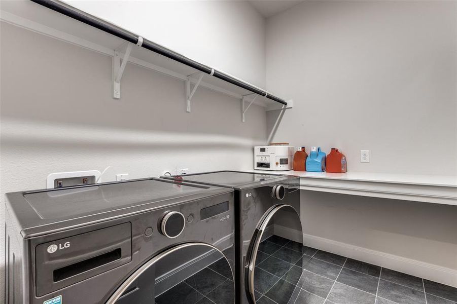 Washroom featuring separate washer and dryer, dark tile patterned floors, and baseboards