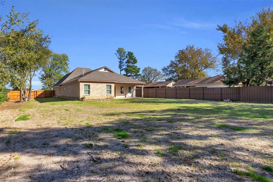 Rear view of property with a fenced backyard, a patio, brick siding, and roof with shingles
