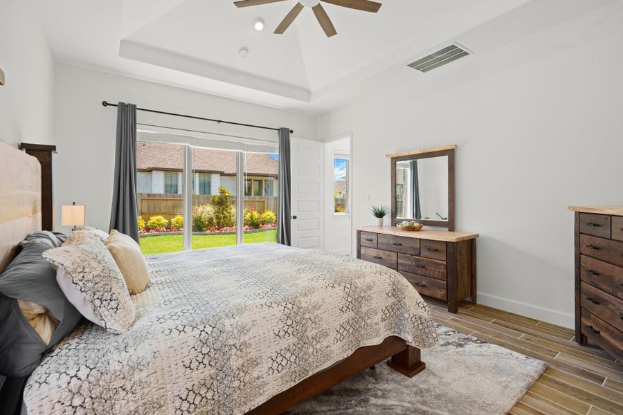 This bedroom features a cozy and inviting atmosphere, with a large window offering plenty of natural light for a view of the backyard. The room has a modern, airy feel, perfect for relaxation.