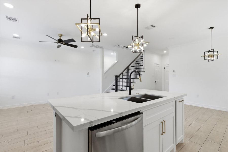 Kitchen with island sink, ceiling fan, pendant lighting, and stainless steel dishwasher.