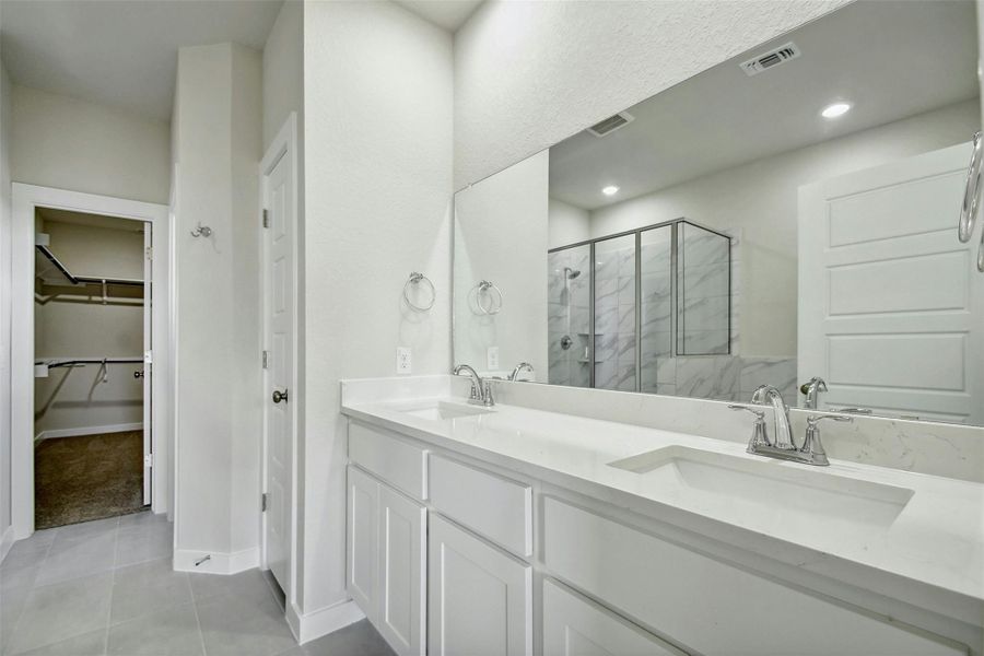 Bathroom with walk in shower, vanity, and tile patterned flooring