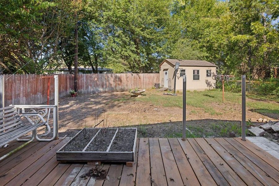 Deck featuring a fenced backyard, a fire pit, and a storage unit