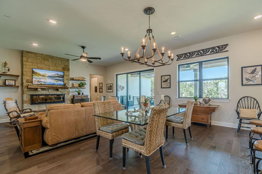 Dining area with ceiling fan, dark wood finished floors, a fireplace, a chandelier, and recessed lighting