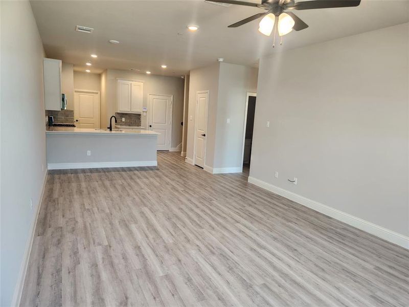 Unfurnished living room featuring ceiling fan, light hardwood / wood-style floors, and sink