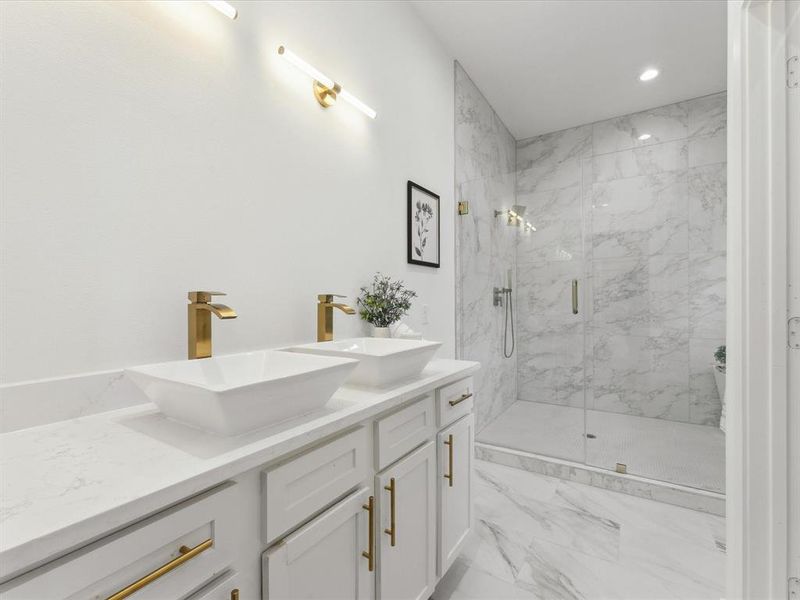 Full bathroom with double vanity, marble finish floor, a marble finish shower, and a sink