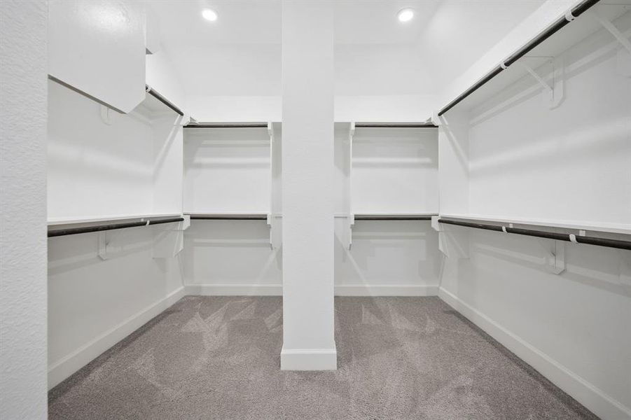 Walk-in closet featuring white shelving systems and dark-toned hanging rods