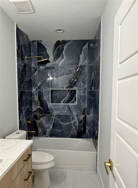 Full tub/shower combination featuring striking dark veined tile surround with a recessed niche Full tub/shower combination featuring striking dark veined tile surround with a recessed niche