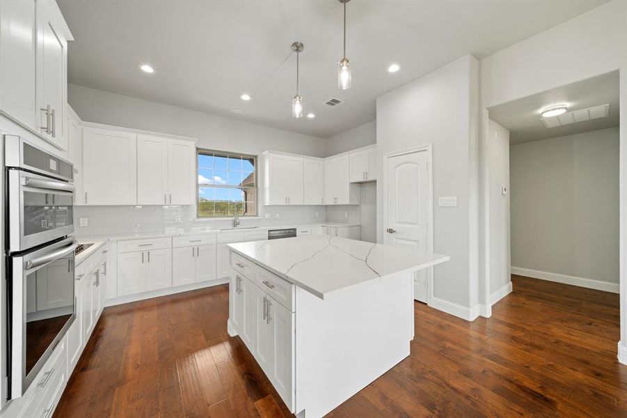 Kitchen featuring white cabinetry, tasteful backsplash, dark hardwood / wood-style flooring, stainless steel appliances, and light stone countertops