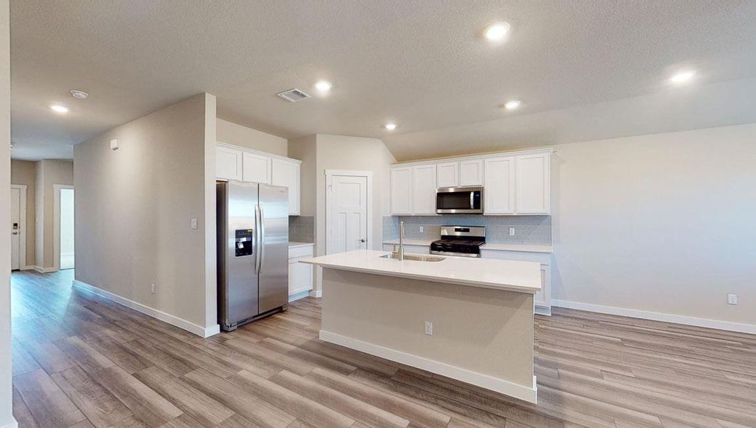 Kitchen featuring white cabinets, appliances with stainless steel finishes, a center island with sink, backsplash, and recessed lighting