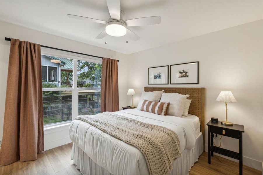 Bedroom with ceiling fan, multiple windows, and hardwood / wood-style floors