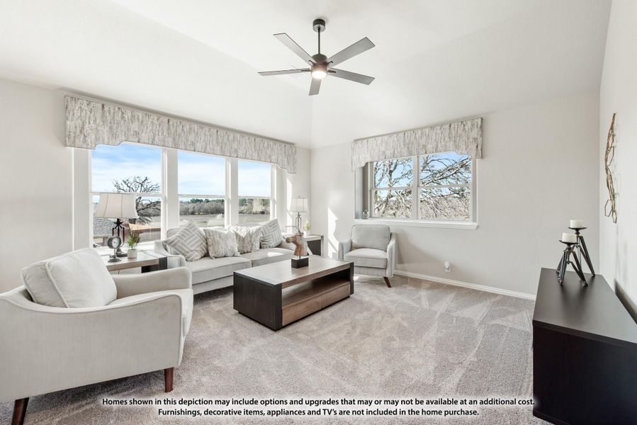 Bright living room with gray sofa, ceiling fan, carpet, and large windows with outdoor views