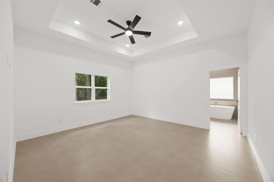 Expansive primary bedroom with tray ceiling, recessed lighting, and private ensuite.