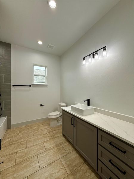 This bathroom features modern fixtures with a sleek white countertop, a vessel sink, and ample cabinet space. It includes a toilet, a small window for natural light, and stylish tile flooring. The design is clean and contemporary, perfect for a refreshing space. This bathroom features modern fixtures with a sleek white countertop, a vessel sink, and ample cabinet space. It includes a toilet, a small window for natural light, and stylish tile flooring. The design is clean and contemporary, perfect for a refreshing space.