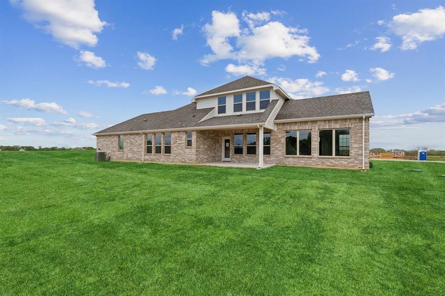 Rear view of property featuring a shingled roof, brick siding, a patio, and a lawn Rear view of property featuring a shingled roof, brick siding, a patio, and a lawn