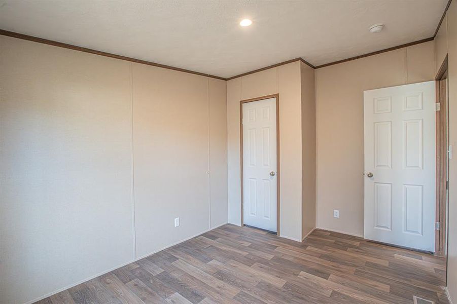 Unfurnished bedroom featuring hardwood / wood-style floors and ornamental molding Unfurnished bedroom featuring hardwood / wood-style floors and ornamental molding