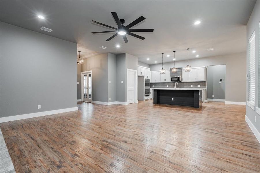 Unfurnished living room with ceiling fan, a sink, light wood-style flooring, recessed lighting, and visible vents Unfurnished living room with ceiling fan, a sink, light wood-style flooring, recessed lighting, and visible vents