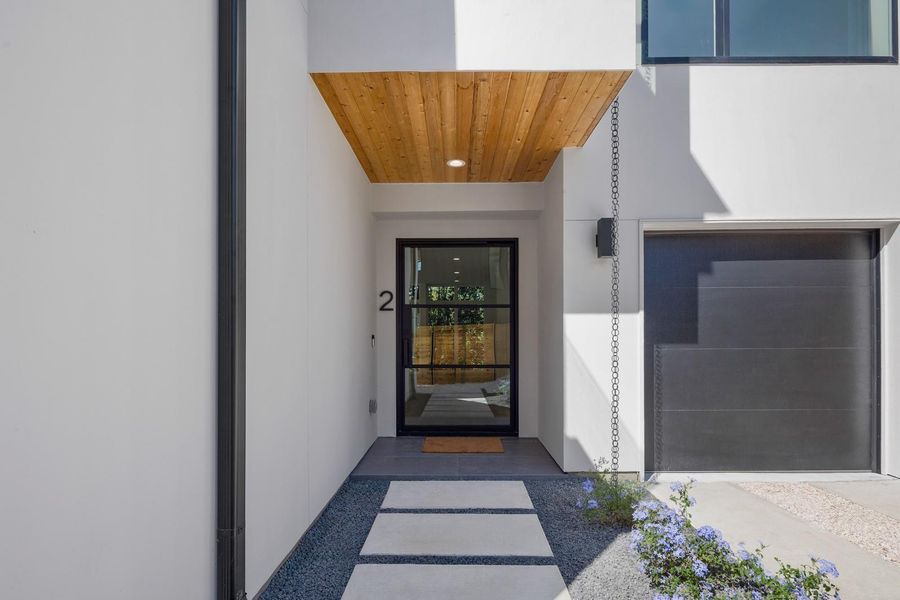 Doorway to property featuring stucco siding and a garage Doorway to property featuring stucco siding and a garage